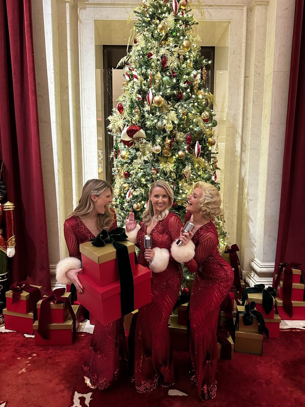 The Roxys in festive red beside a Christmas tree at a luxury London hotel